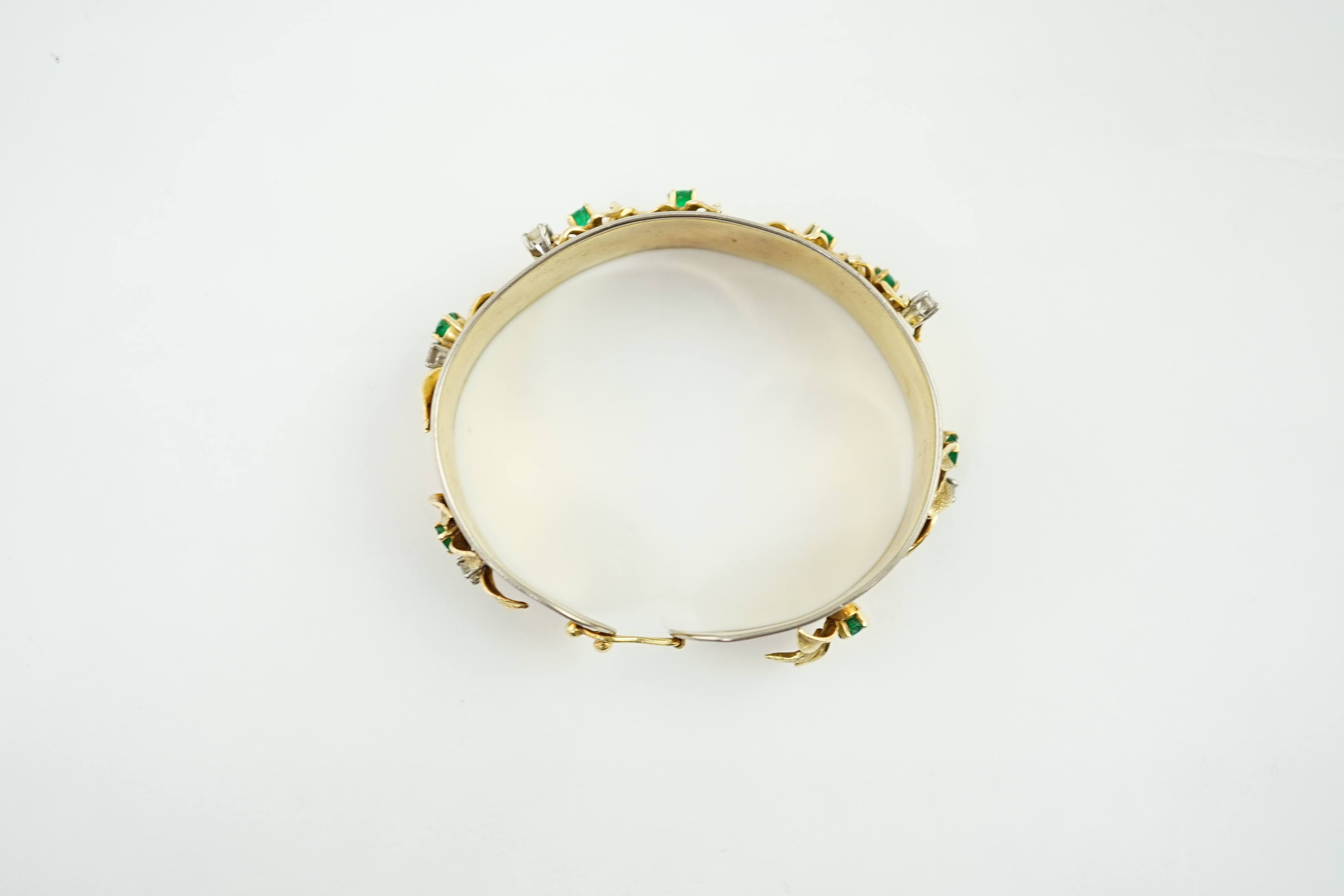 A recent Schwartz 18k gold, emerald and diamond cluster set open bangle with clasp